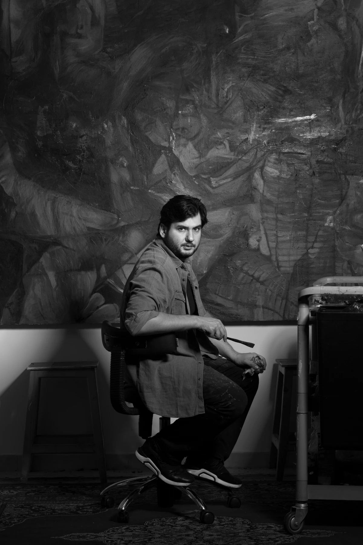 ALIREZA JAHROMI seated in the studio, holding a painting tool